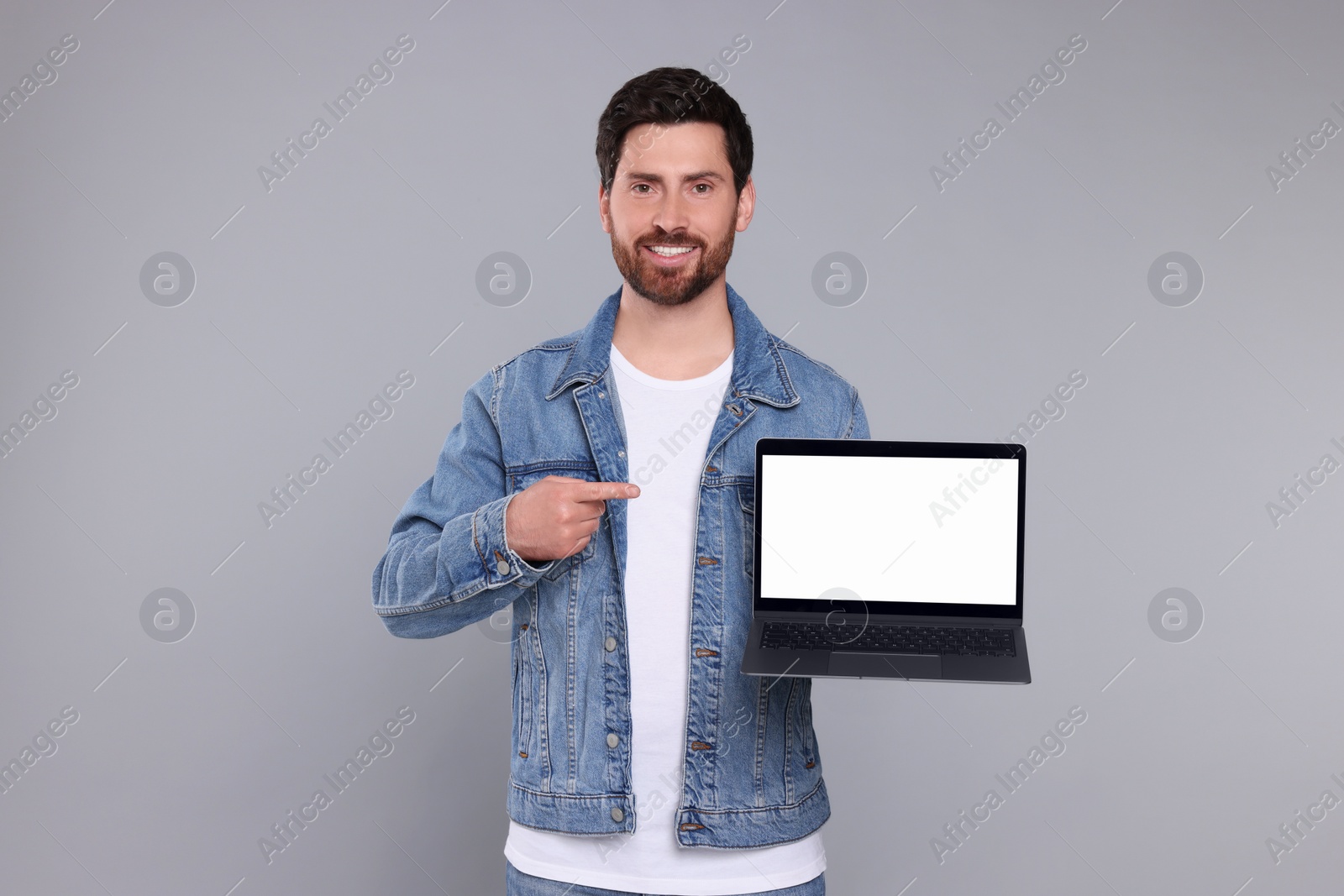 Photo of Happy man with laptop on light grey background