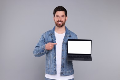 Happy man with laptop on light grey background