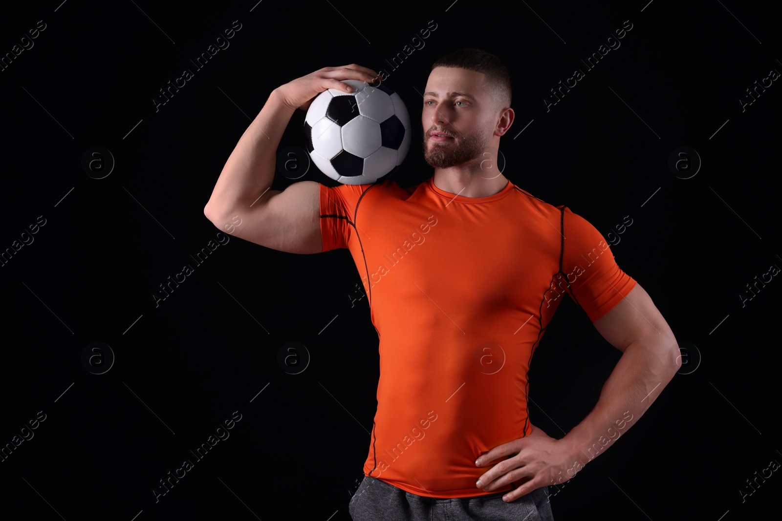 Photo of Athletic young man with soccer ball on black background