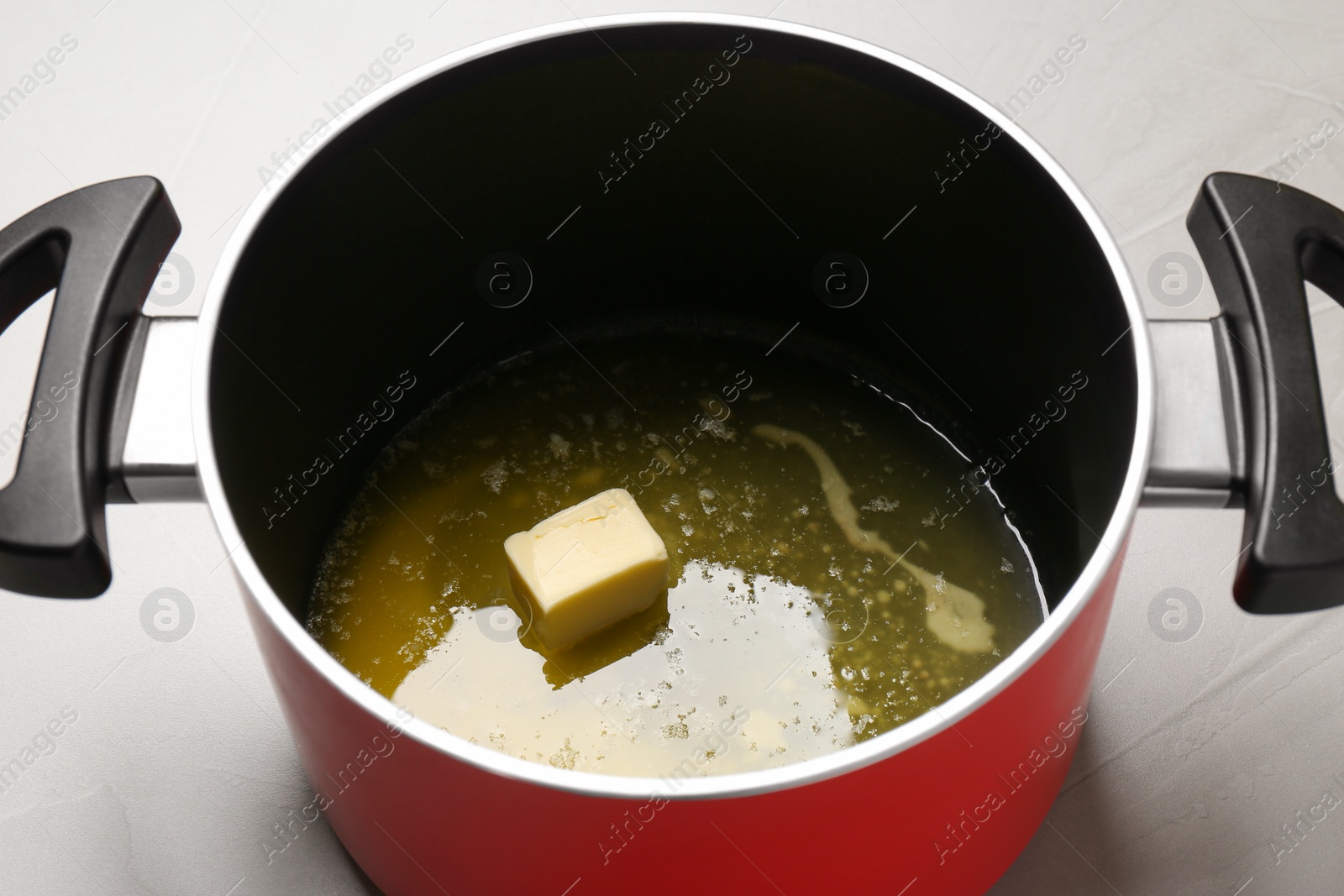 Photo of Pot with melting butter on grey table, closeup