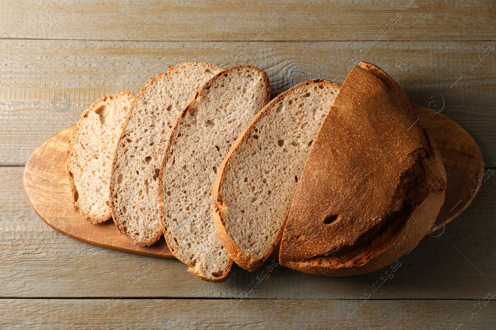 Photo of Freshly baked cut sourdough bread on wooden table, top view