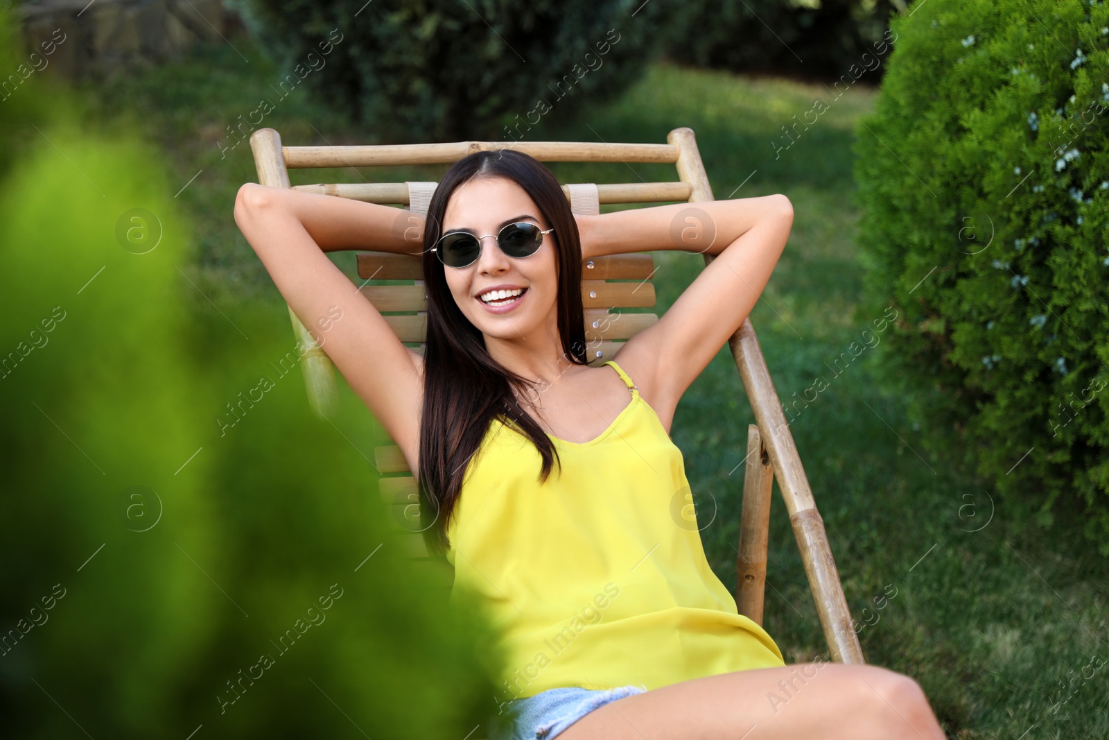 Photo of Beautiful young woman relaxing in deckchair at garden