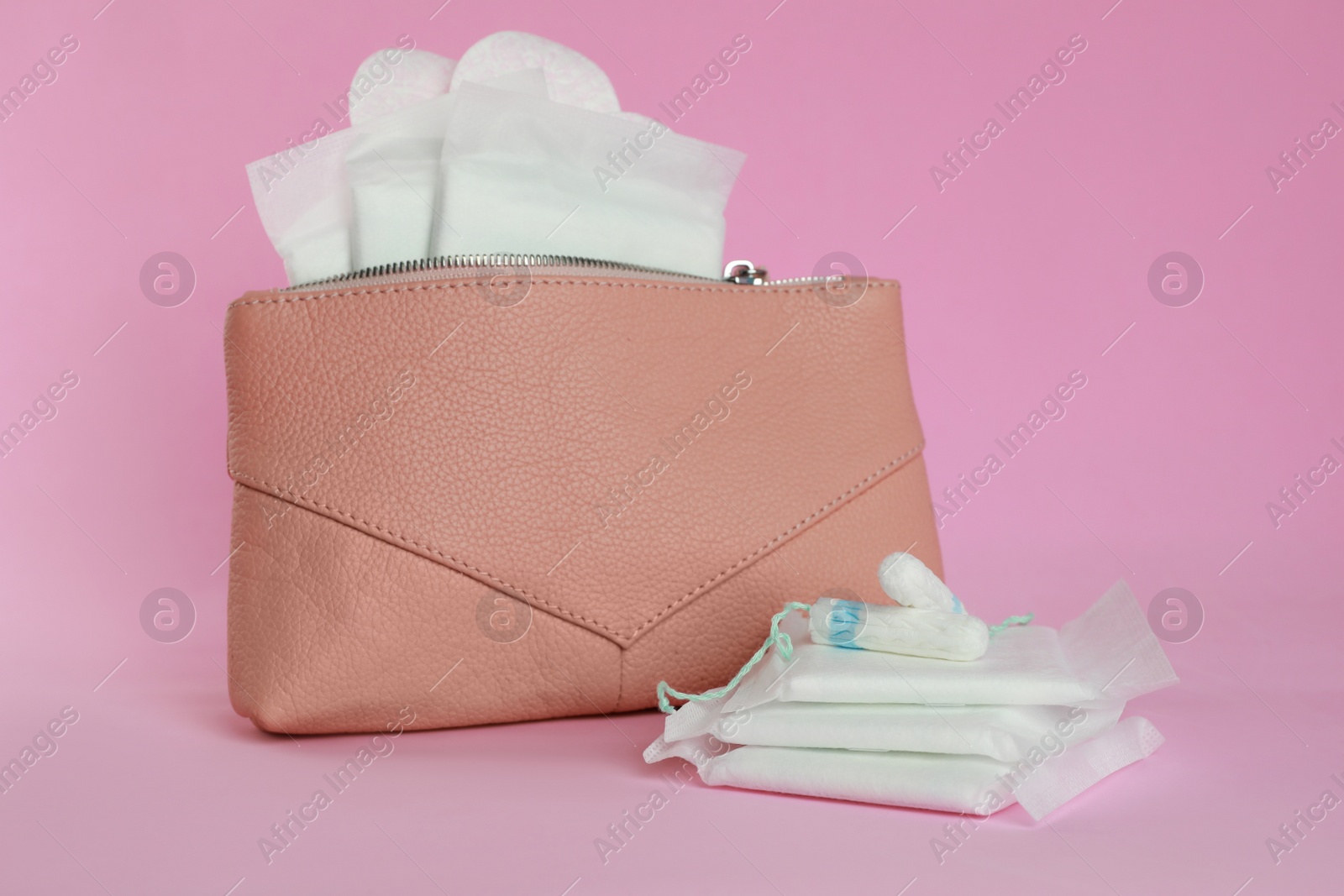 Photo of Bag with menstrual pads, pantyliners and tampons on pink background