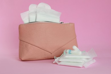 Photo of Bag with menstrual pads, pantyliners and tampons on pink background