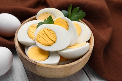 Fresh hard boiled eggs and parsley on white wooden table, closeup