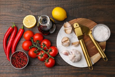 Different fresh ingredients for marinade and garlic press on wooden table, flat lay
