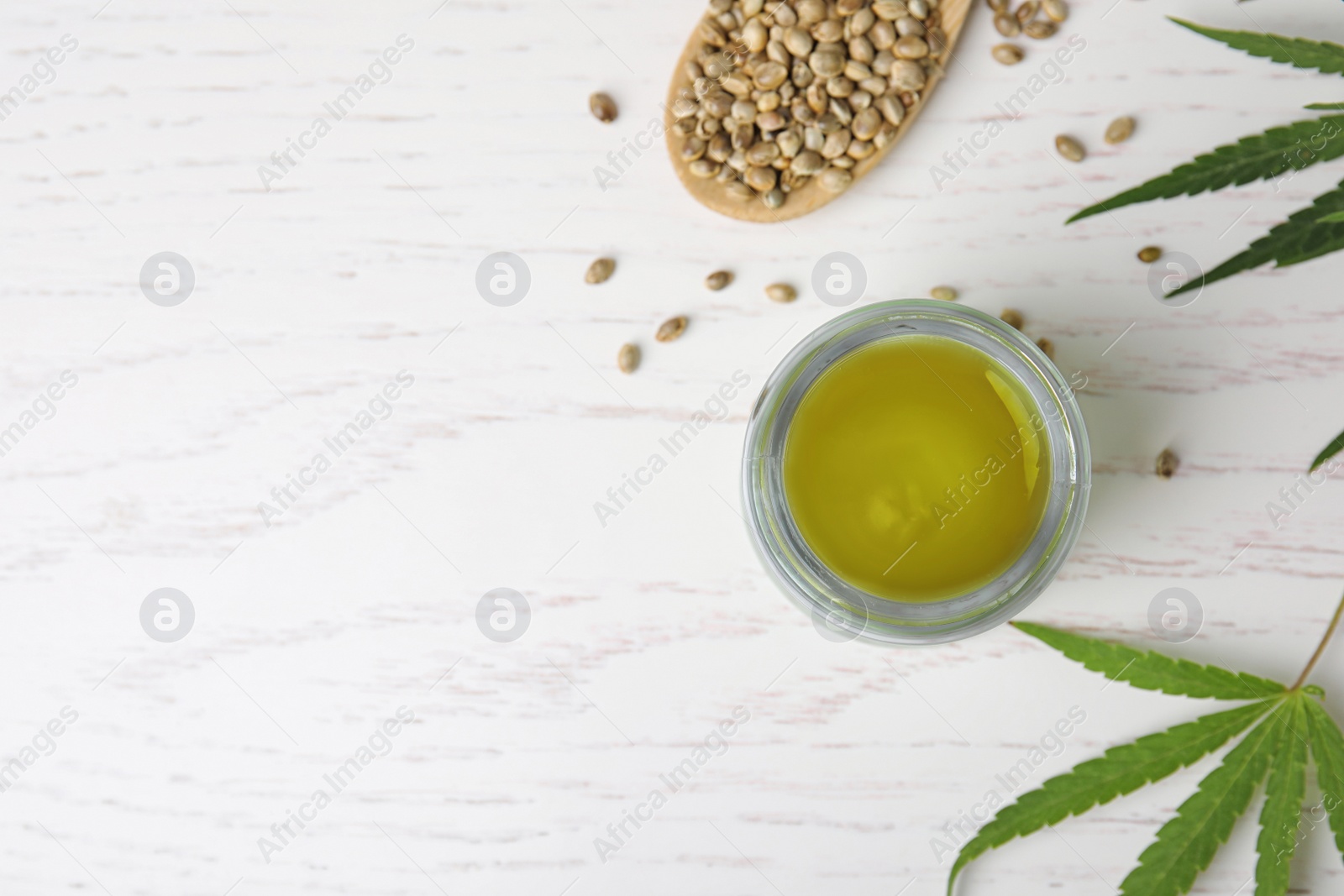 Photo of Jar of hemp cream and seeds on white wooden table, flat lay with space for text. Organic cosmetics