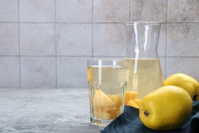 Photo of Delicious quince drink and fresh fruits on grey table. Space for text