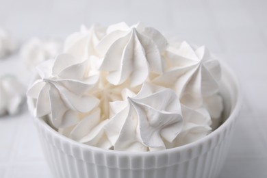 Photo of Delicious meringue cookies in bowl on white table, closeup