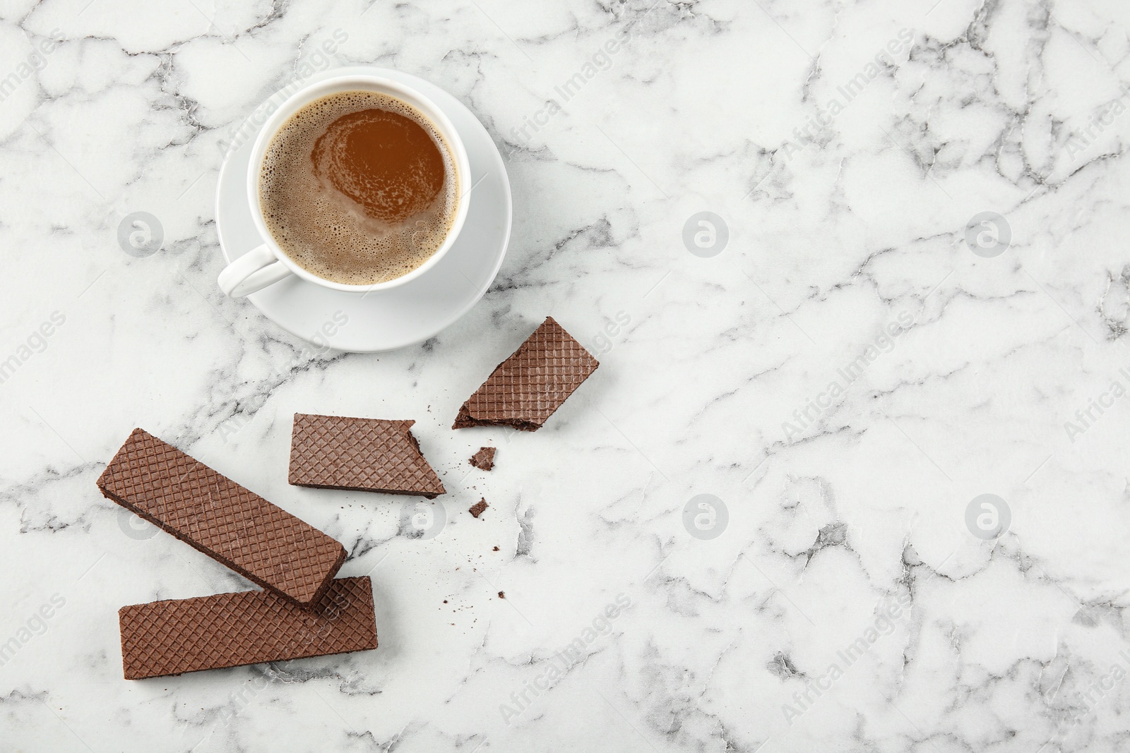 Photo of Delicious chocolate wafers with cup of coffee on marble background, top view. Space for text