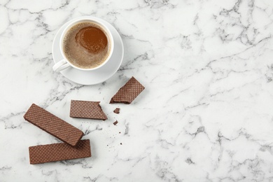 Photo of Delicious chocolate wafers with cup of coffee on marble background, top view. Space for text