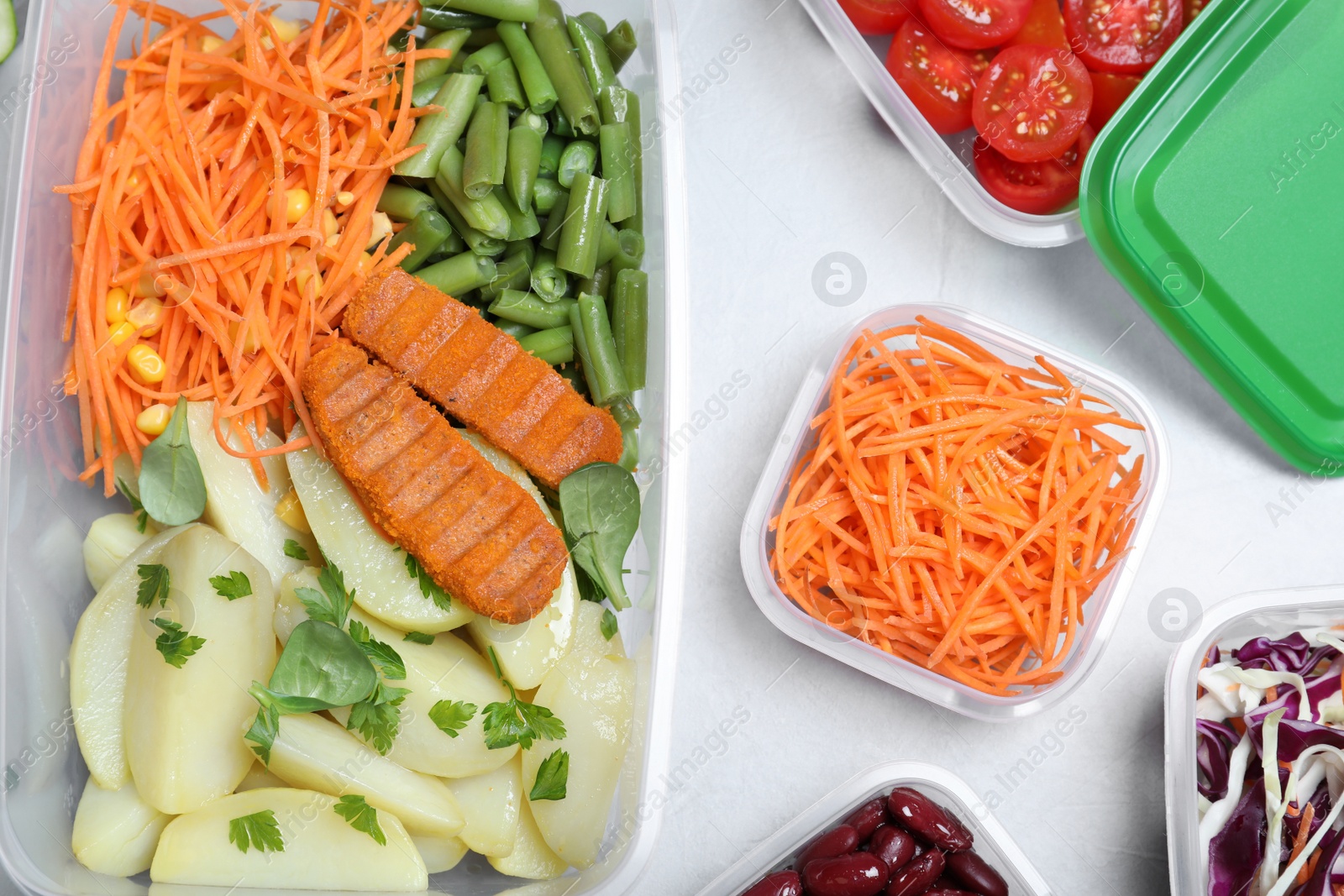 Photo of Set of plastic containers with fresh food on light table, flat lay