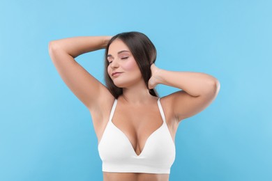 Portrait of young woman with beautiful breast on light blue background