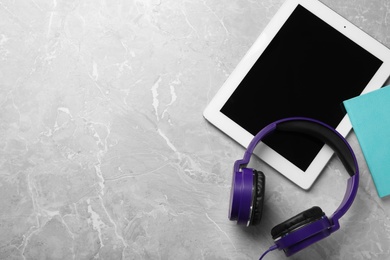 Flat lay composition with headphones and tablet on table. Space for text