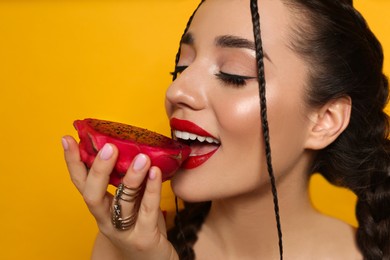Young woman with fresh pitahaya on yellow background, closeup. Exotic fruit