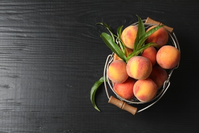 Basket with ripe peaches on wooden background, top view