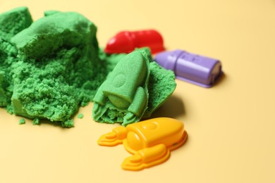 Photo of Bright kinetic sand and plastic toys on beige background