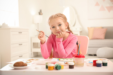 Cute little child painting at table in room