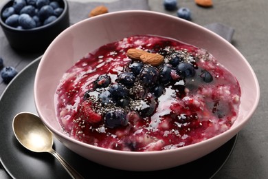 Photo of Tasty oatmeal porridge with toppings on grey table, closeup