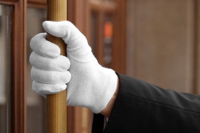 Photo of Butler in suit and white gloves opening hotel door, closeup