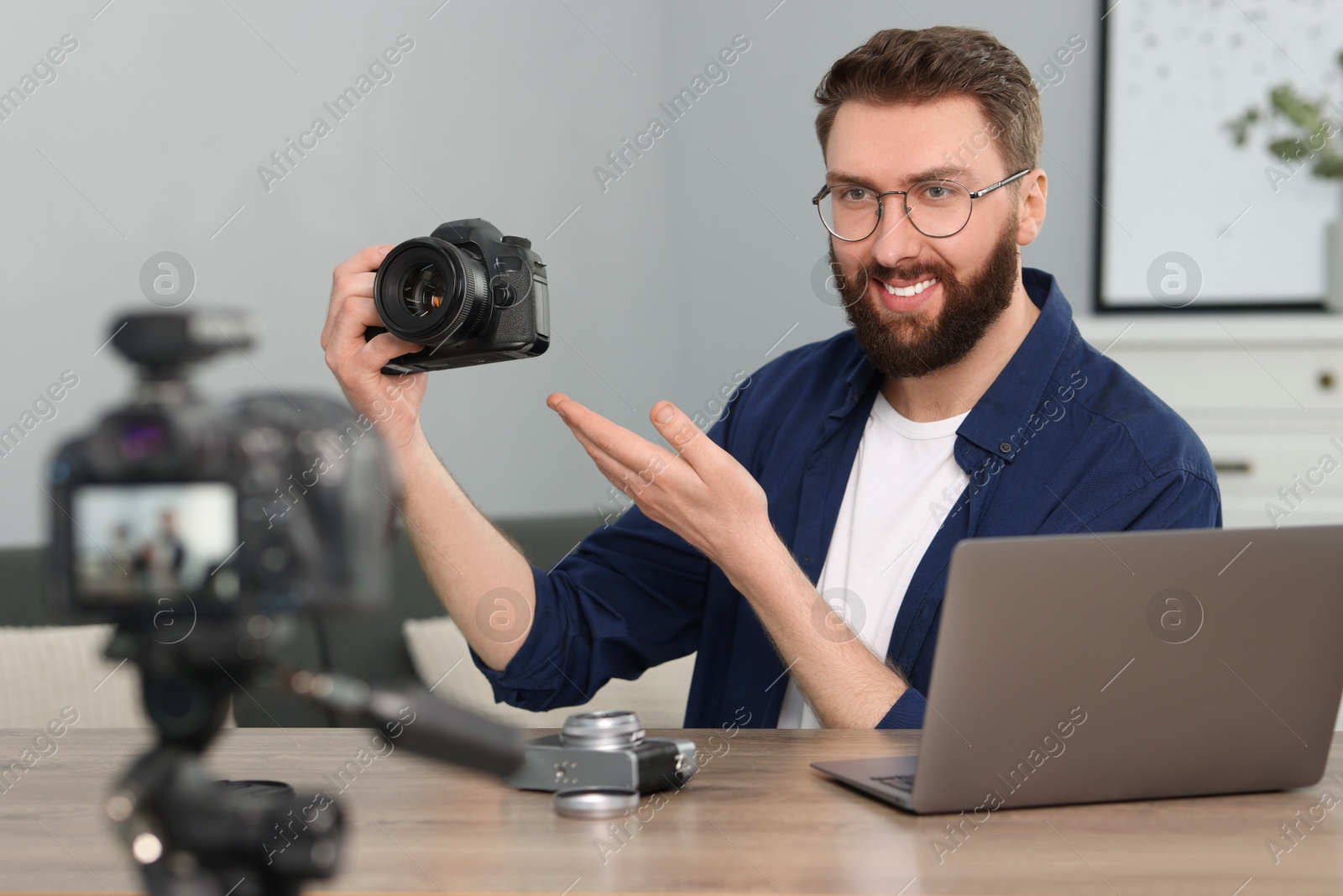 Photo of Smiling technology blogger recording video review about cameras at home