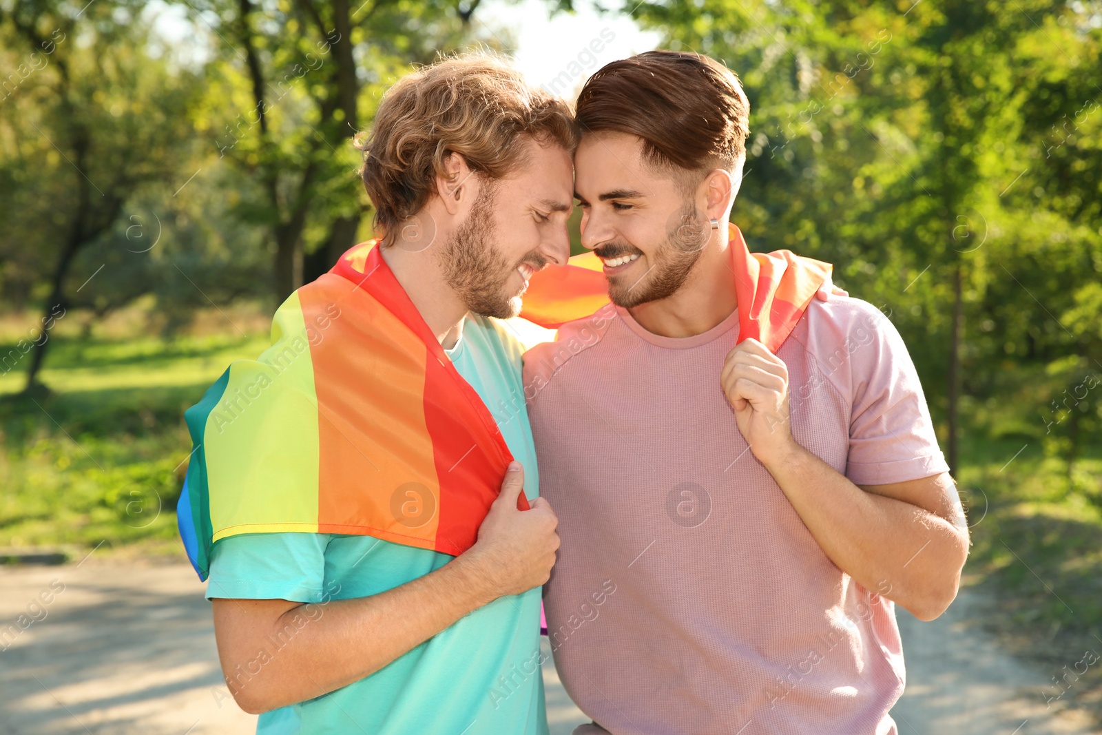 Photo of Happy gay couple with rainbow flag outdoors