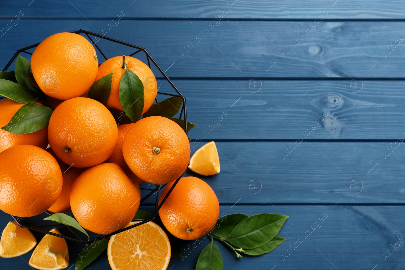 Photo of Delicious ripe oranges on blue wooden table, flat lay. Space for text