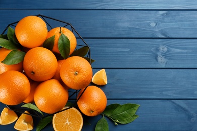 Delicious ripe oranges on blue wooden table, flat lay. Space for text