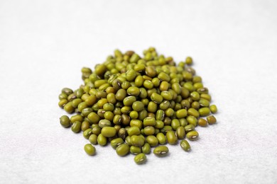 Photo of Pile of green mung beans on light grey table, closeup