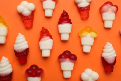 Delicious gummy ice cream cones candies on orange background, flat lay