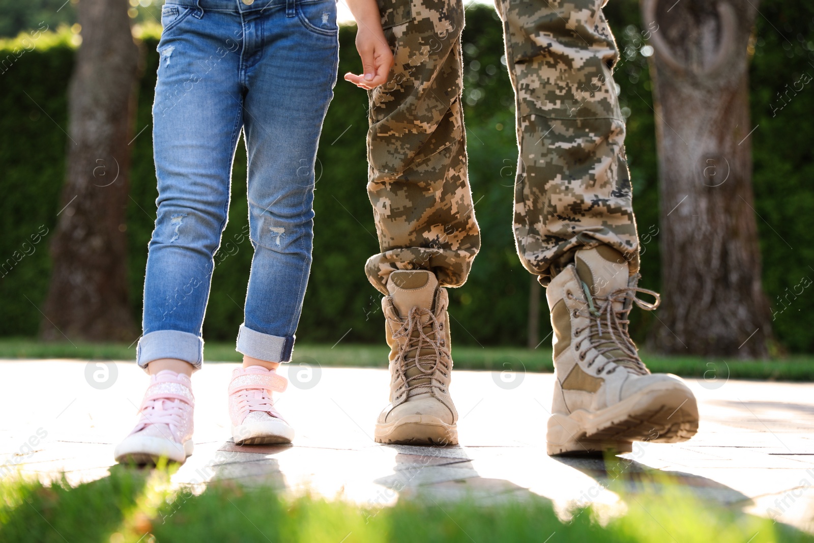 Photo of Father in military uniform walking with his daughter at sunny park, closeup