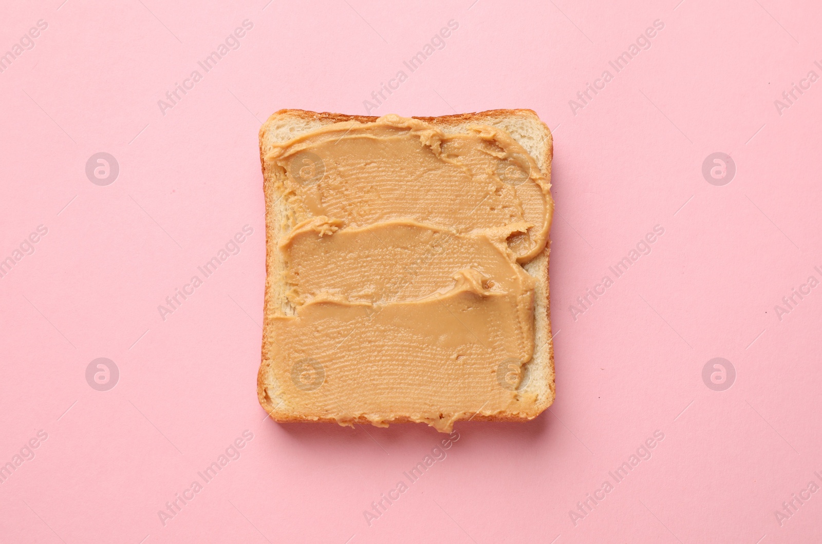 Photo of Tasty peanut butter sandwich on pink background, top view