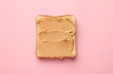 Photo of Tasty peanut butter sandwich on pink background, top view