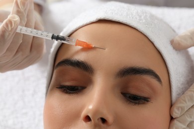 Photo of Doctor giving facial injection to young woman in clinic, closeup. Cosmetic surgery