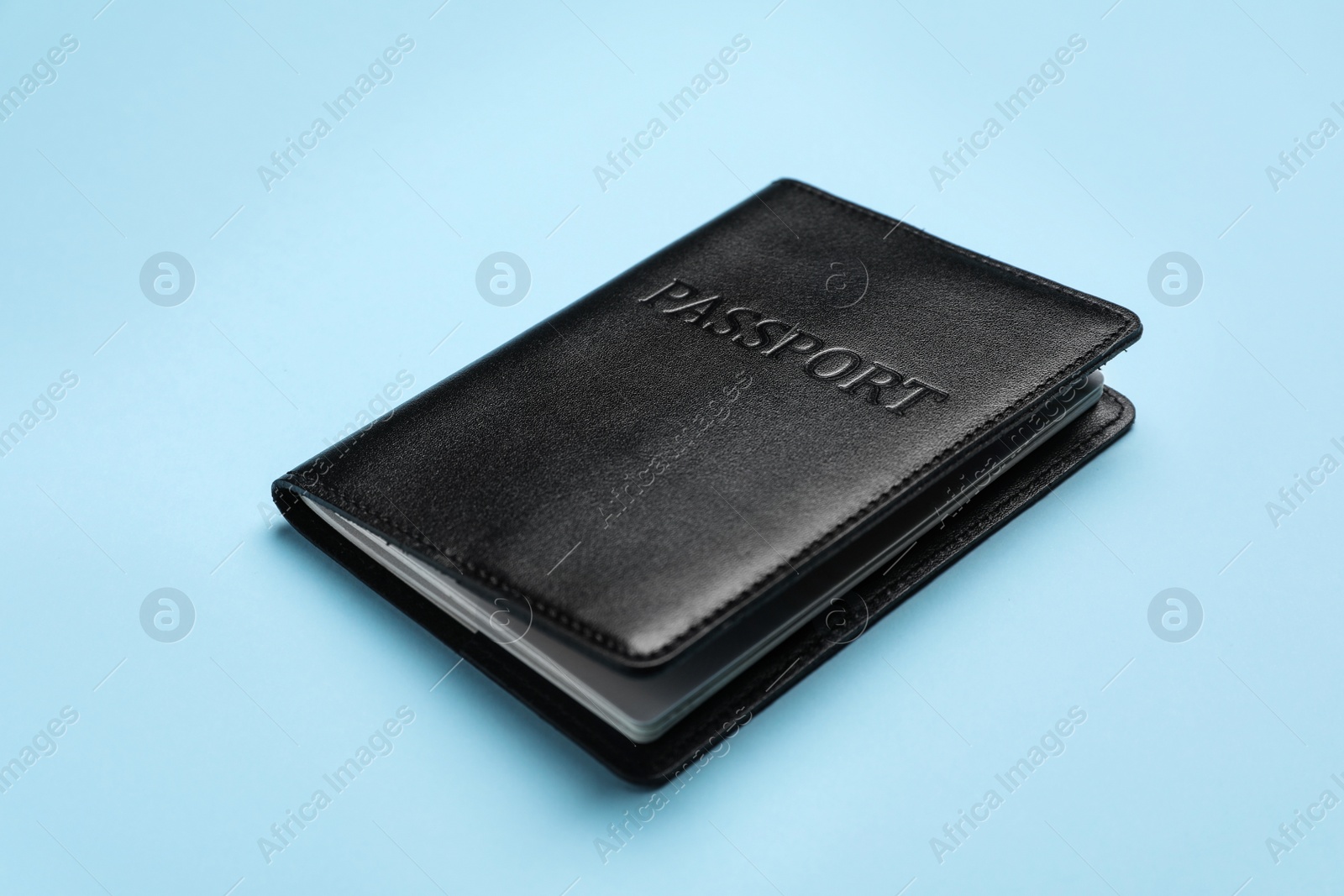 Photo of Passport in black leather case on light blue background