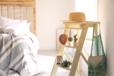 Decorative ladder with different stuff in stylish bedroom. Idea for interior design