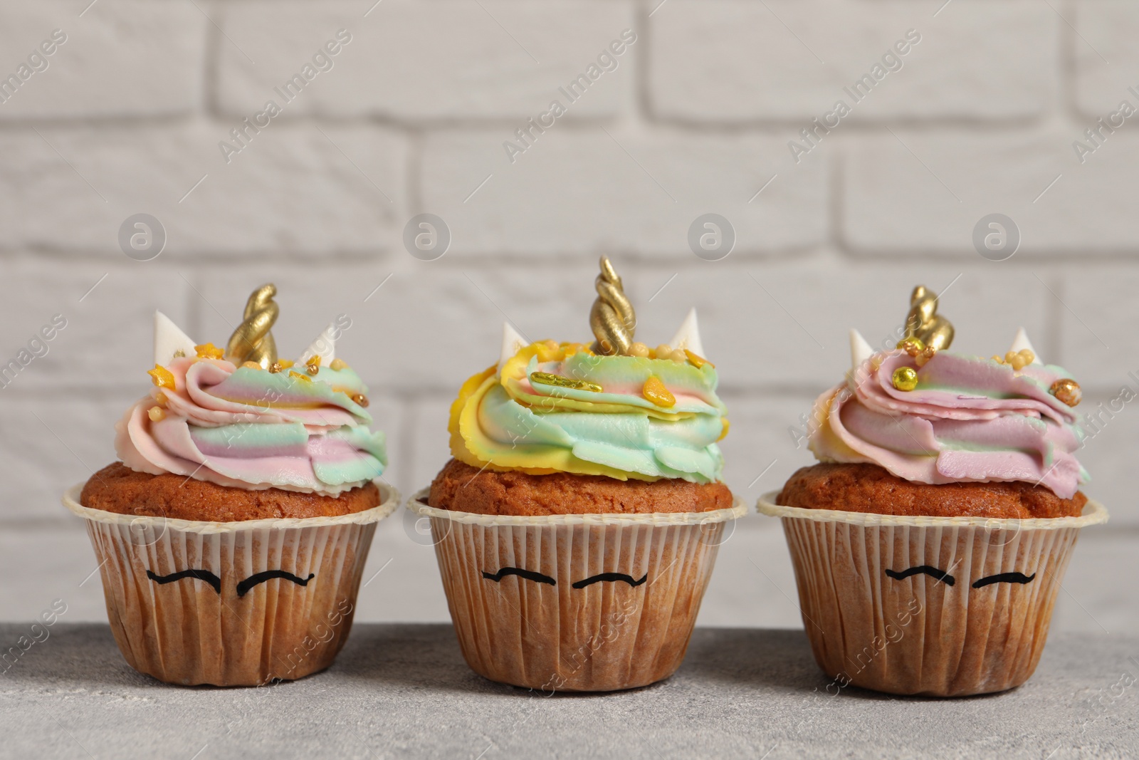 Photo of Cute sweet unicorn cupcakes on light grey table