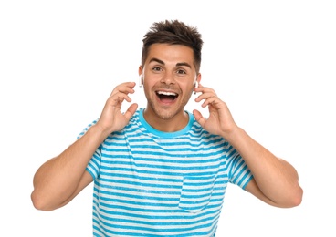 Happy young man listening to music through wireless earphones on white background