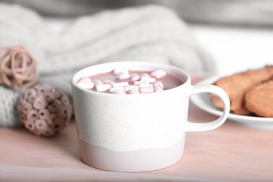 Photo of Cup of aromatic cacao with marshmallows on wooden tray near window