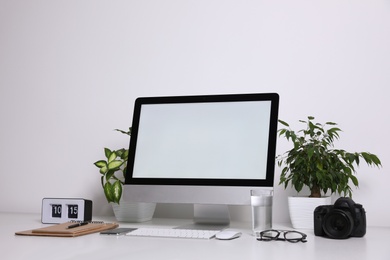 Photo of Comfortable workplace with modern computer on table near white wall. Space for text