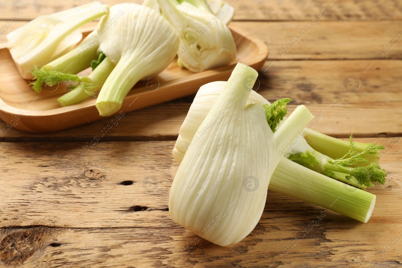 Photo of Fresh raw fennel bulbs on wooden table, closeup