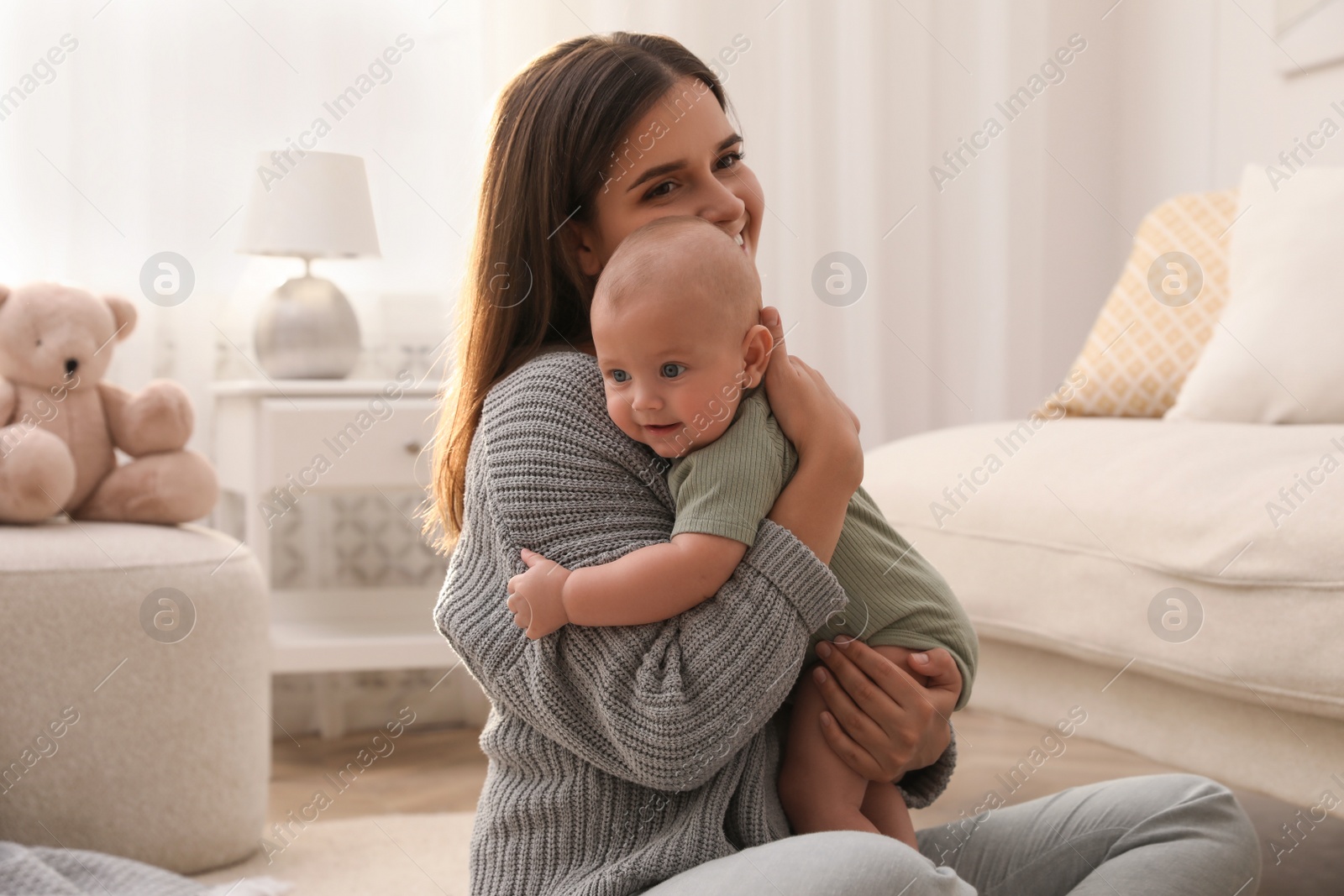 Photo of Young woman with her little baby on floor at home