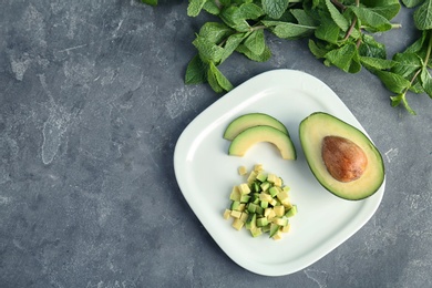 Flat lay composition with ripe avocado and mint on grey background