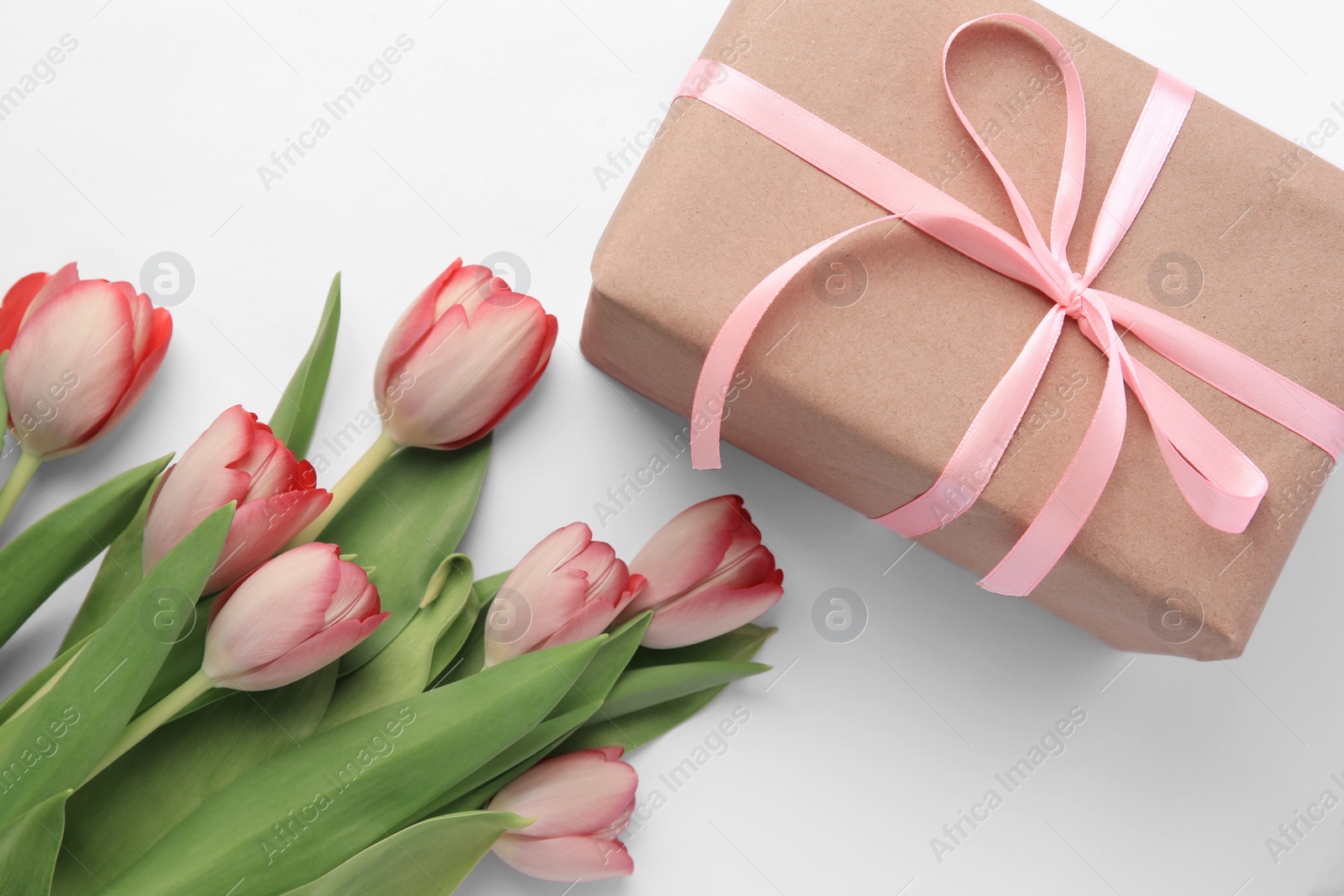 Photo of Beautiful gift box with bow and pink tulips on white background, flat lay