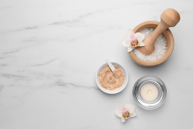 Flat lay composition with different spa products and flowers on white marble table. Space for text