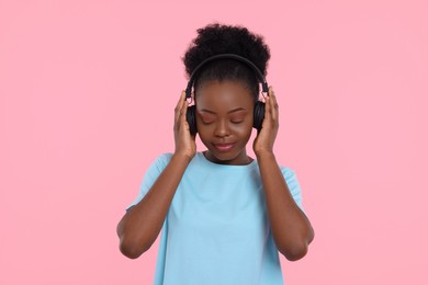 Photo of Young woman in headphones enjoying music on pink background