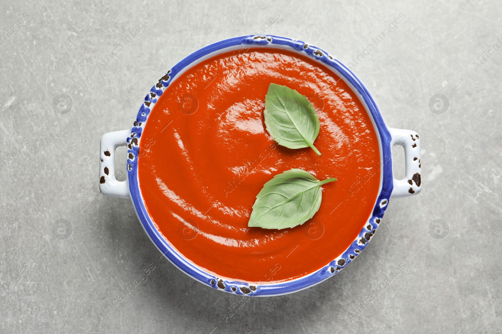 Photo of Dish with fresh homemade tomato soup on grey background, top view