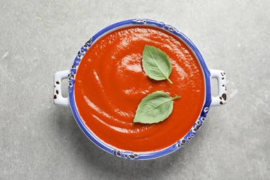 Dish with fresh homemade tomato soup on grey background, top view