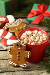 Photo of Tasty gingerbread man cookie and cocoa with marshmallows on wooden table