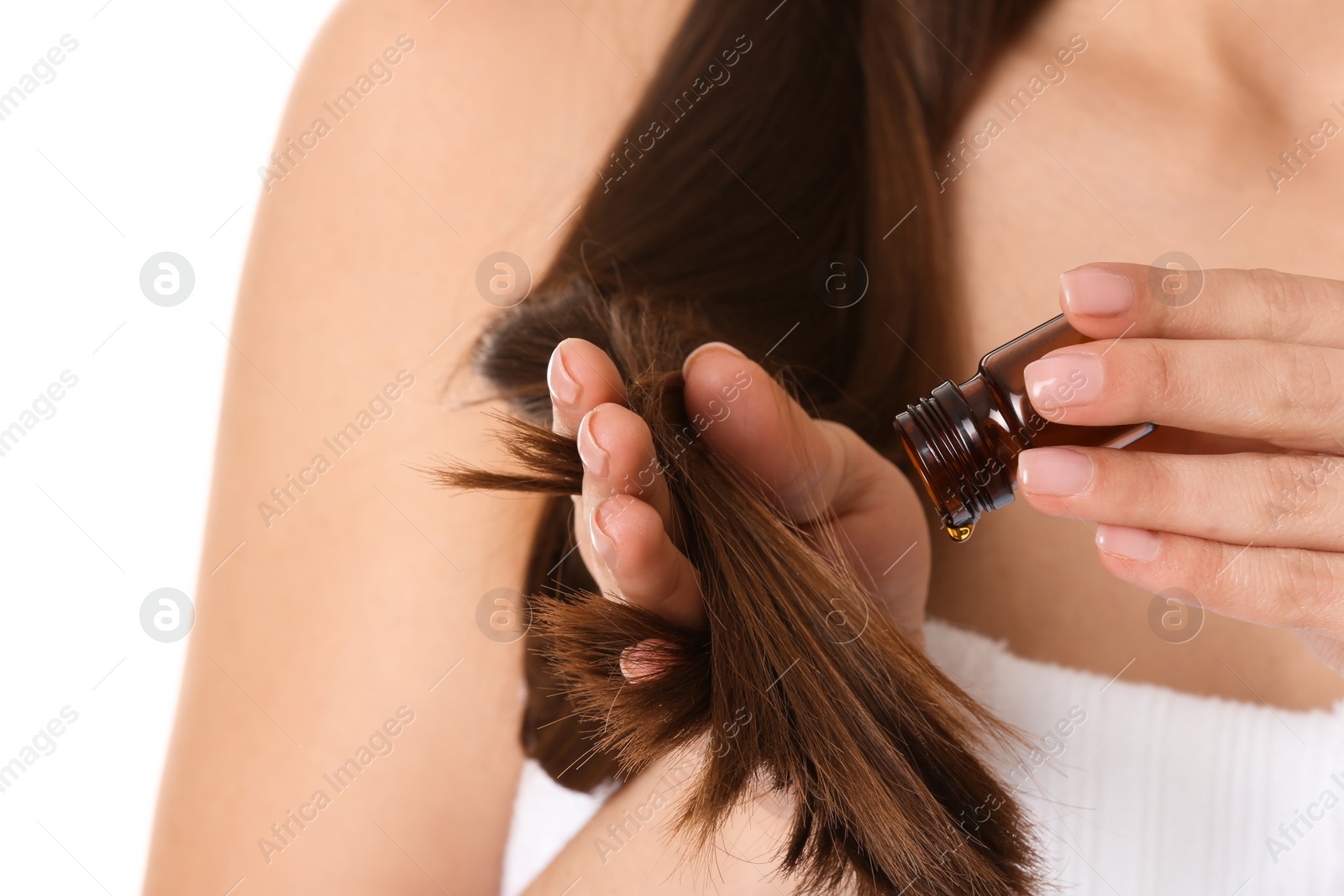 Photo of Woman applying oil onto hair against white background, closeup